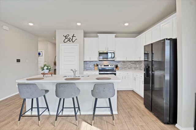 kitchen featuring appliances with stainless steel finishes, a center island with sink, white cabinetry, and sink