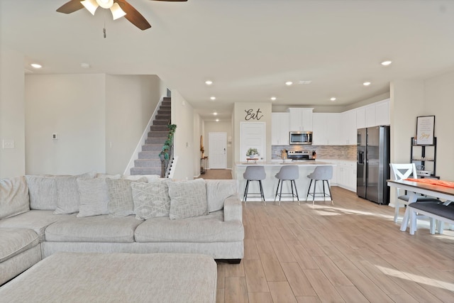 living room with ceiling fan and light wood-type flooring