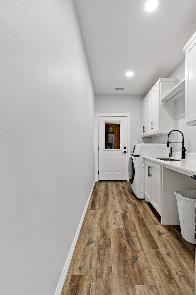 laundry area featuring sink, dark hardwood / wood-style floors, and cabinets