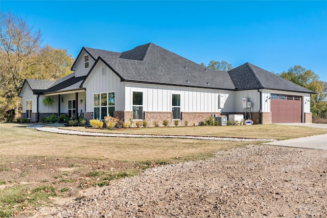 exterior space featuring a garage, cooling unit, and a lawn