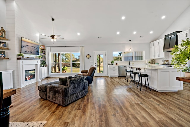 living room featuring ceiling fan, high vaulted ceiling, and light wood-type flooring