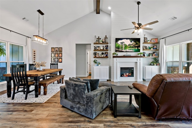 living room with high vaulted ceiling, a large fireplace, dark hardwood / wood-style flooring, beamed ceiling, and ceiling fan