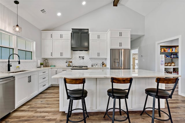 kitchen featuring light stone counters, sink, stainless steel appliances, and a center island