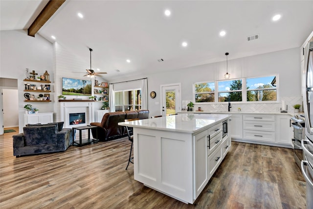 kitchen featuring hanging light fixtures, hardwood / wood-style floors, white cabinets, and beamed ceiling