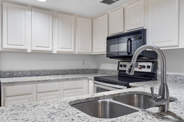 kitchen with light stone countertops, white cabinetry, and stainless steel electric range