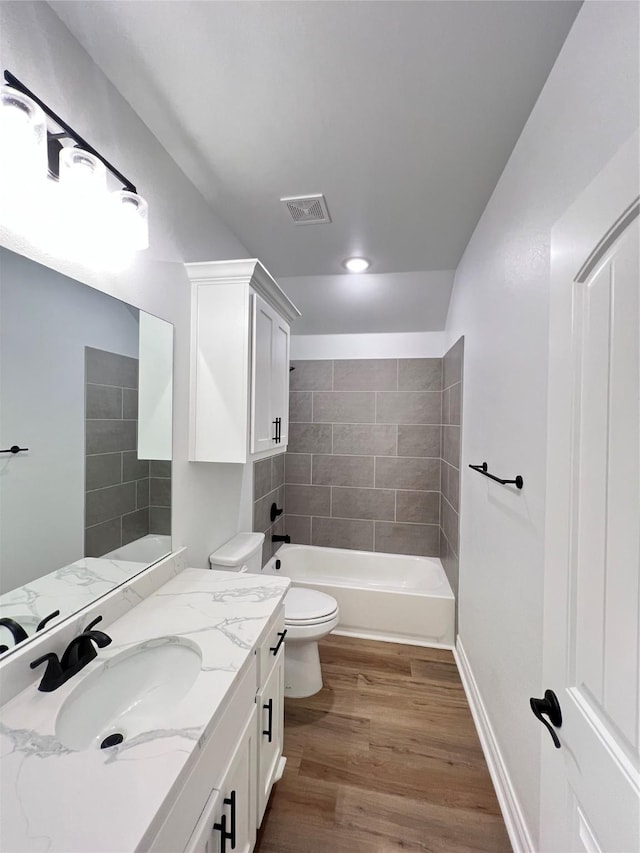 full bathroom featuring vanity, hardwood / wood-style flooring, toilet, and tiled shower / bath combo