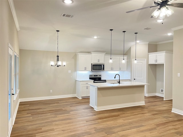 kitchen featuring backsplash, white cabinets, a center island with sink, hanging light fixtures, and appliances with stainless steel finishes