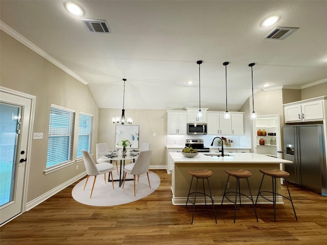 kitchen featuring pendant lighting, a kitchen island with sink, white cabinets, sink, and appliances with stainless steel finishes