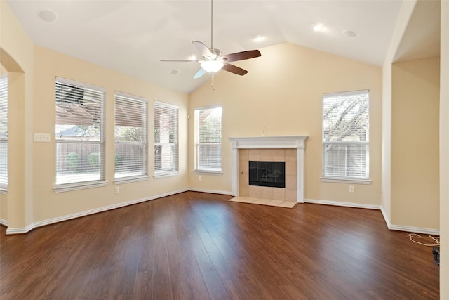 unfurnished living room with a tile fireplace, vaulted ceiling, dark hardwood / wood-style floors, and ceiling fan