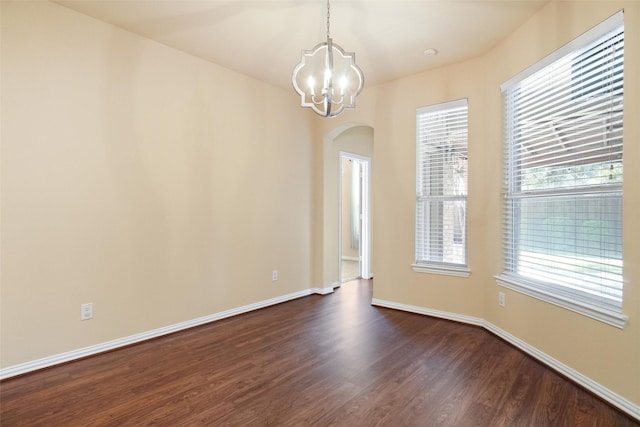 empty room featuring dark wood-type flooring and an inviting chandelier