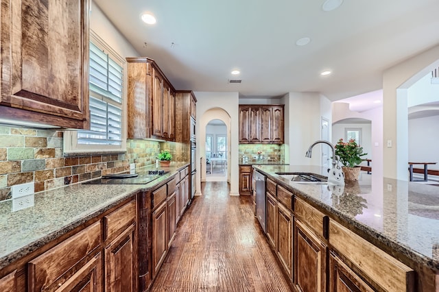 kitchen with dishwasher, sink, wood-type flooring, stone countertops, and black electric cooktop