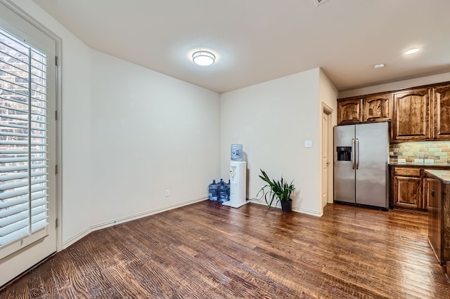 kitchen with stainless steel refrigerator with ice dispenser, dark hardwood / wood-style flooring, and backsplash