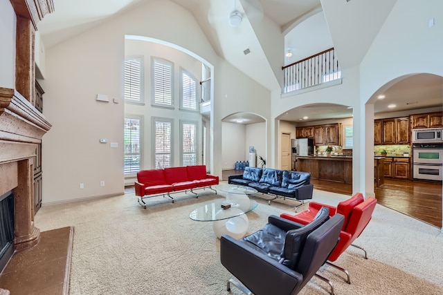 carpeted living room featuring a fireplace and a high ceiling