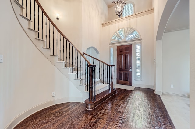 foyer entrance with a towering ceiling, a chandelier, and hardwood / wood-style flooring