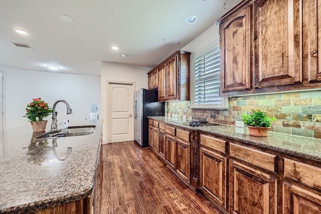 kitchen with stone counters, black electric stovetop, sink, dark hardwood / wood-style flooring, and stainless steel fridge with ice dispenser