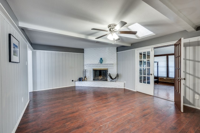 unfurnished living room with beam ceiling, a skylight, french doors, dark hardwood / wood-style floors, and a fireplace