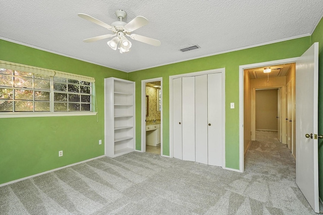 unfurnished bedroom featuring light carpet, a textured ceiling, ceiling fan, and ensuite bath