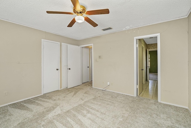 unfurnished bedroom with ceiling fan, light carpet, and a textured ceiling