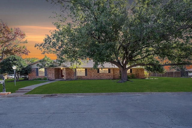 ranch-style house with brick siding, fence, and a yard