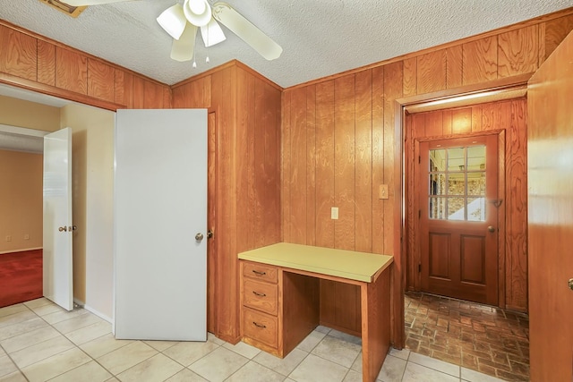 interior space with a textured ceiling, ceiling fan, and wood walls