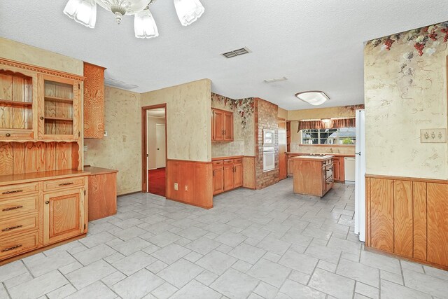 kitchen with tasteful backsplash, a center island, a textured ceiling, and white appliances