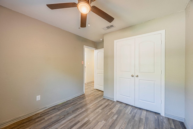 unfurnished bedroom with hardwood / wood-style floors, a closet, and ceiling fan