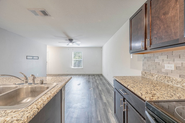 kitchen with ceiling fan, sink, dark hardwood / wood-style floors, backsplash, and dark brown cabinets