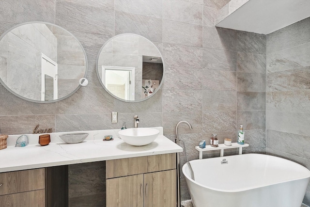 bathroom with tasteful backsplash, a tub to relax in, vanity, and tile walls