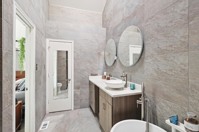 bathroom with tile walls, vanity, and toilet