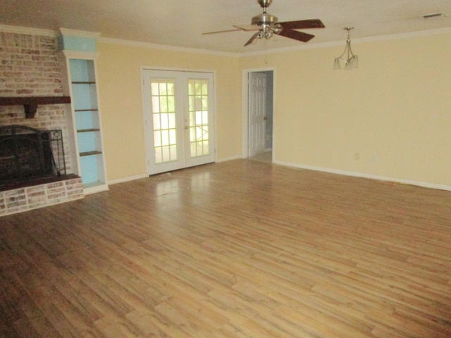 unfurnished living room with french doors, a brick fireplace, ceiling fan, crown molding, and light hardwood / wood-style flooring