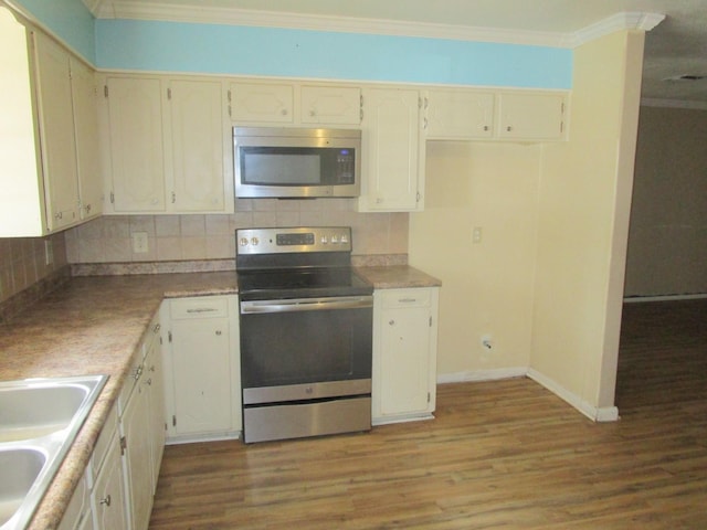 kitchen with tasteful backsplash, light wood-type flooring, ornamental molding, and appliances with stainless steel finishes