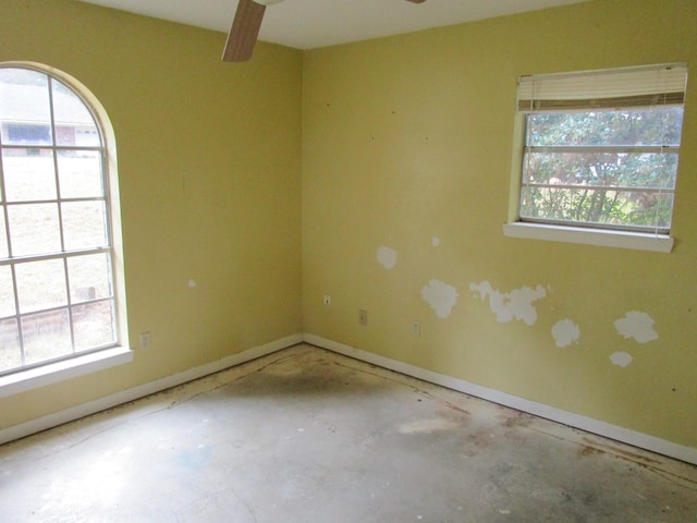 empty room featuring a wealth of natural light, ceiling fan, and concrete floors