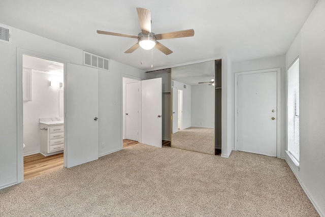 unfurnished bedroom with light carpet, ensuite bath, and ceiling fan