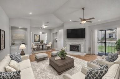 living room with a brick fireplace, light hardwood / wood-style flooring, ceiling fan, and vaulted ceiling