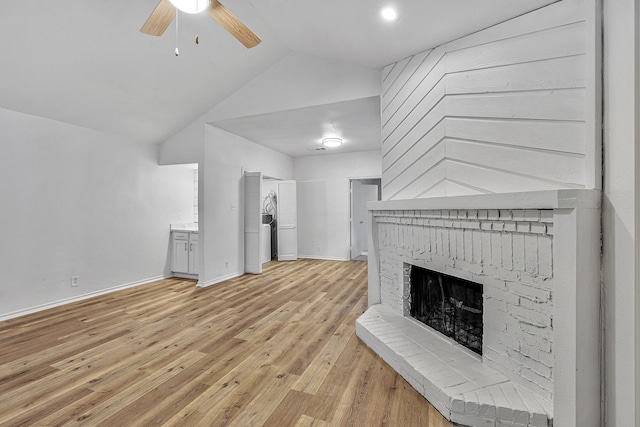 unfurnished living room with ceiling fan, a fireplace, light hardwood / wood-style floors, and vaulted ceiling