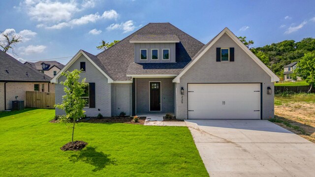 view of front of property featuring a garage, central air condition unit, and a front lawn