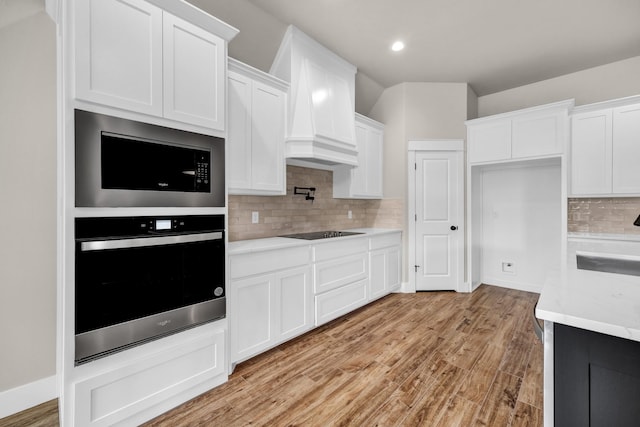 kitchen featuring white cabinetry, built in microwave, light hardwood / wood-style flooring, and oven