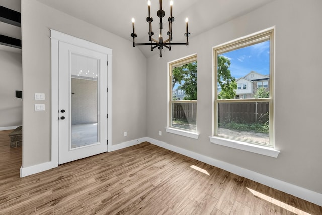 unfurnished dining area featuring light hardwood / wood-style flooring and a notable chandelier