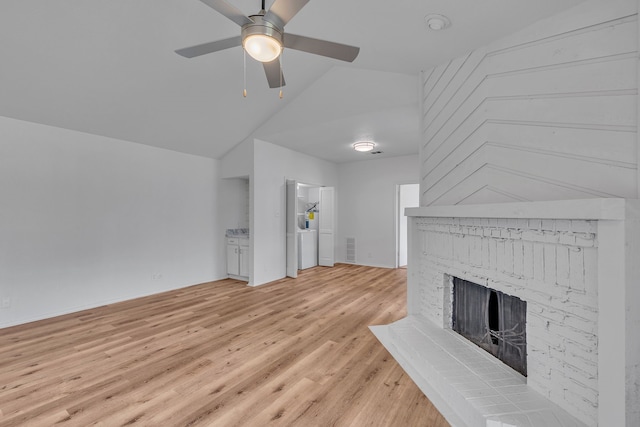 unfurnished living room with vaulted ceiling, light wood-type flooring, ceiling fan, and a fireplace