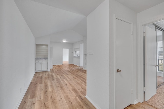 hall with light hardwood / wood-style flooring and vaulted ceiling