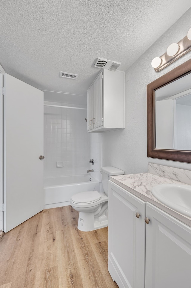 full bathroom with wood-type flooring, toilet, vanity, and a textured ceiling