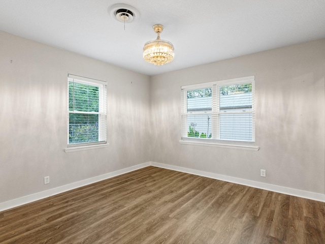 spare room featuring wood-type flooring and a notable chandelier