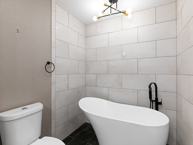 bathroom with a bathing tub, tile walls, an inviting chandelier, and toilet