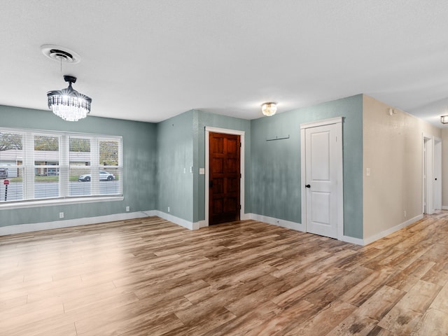 unfurnished room with light wood-type flooring and a chandelier