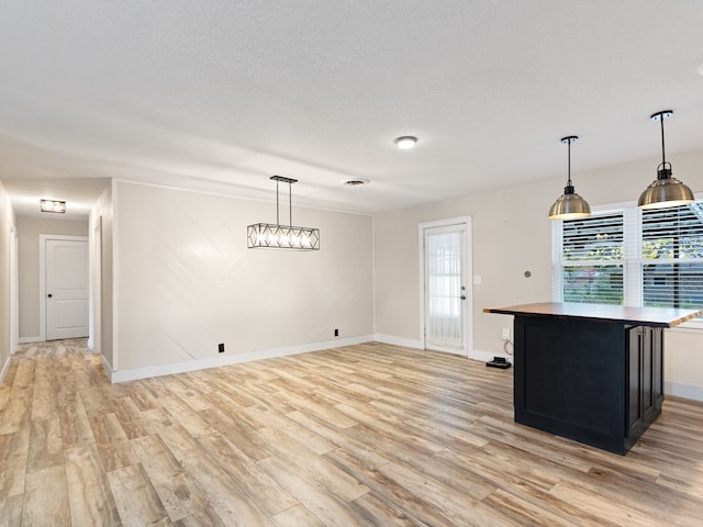 kitchen featuring decorative light fixtures, a textured ceiling, and light hardwood / wood-style flooring