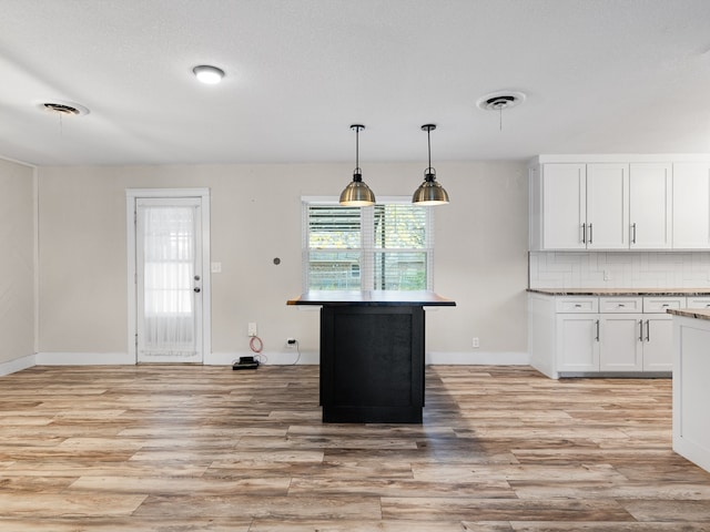 kitchen with pendant lighting, backsplash, light hardwood / wood-style flooring, and white cabinetry