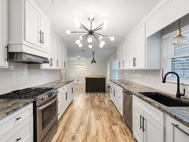 kitchen featuring appliances with stainless steel finishes, sink, white cabinets, and dark stone counters