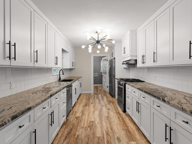 kitchen featuring white cabinetry, stainless steel appliances, and dark stone counters