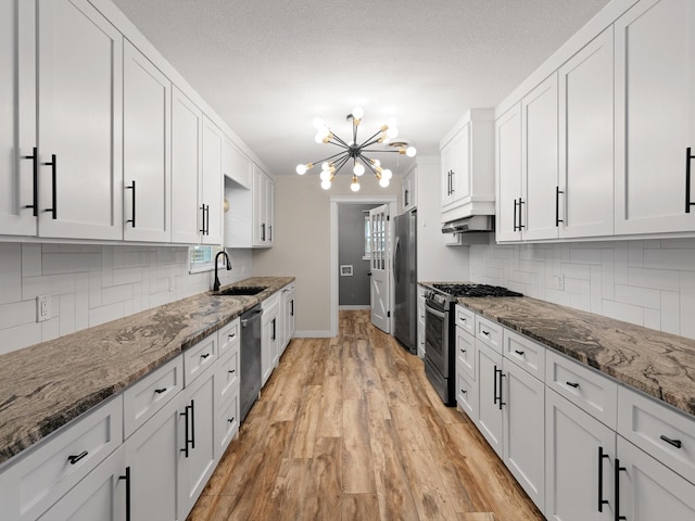 kitchen with dark stone countertops, white cabinets, and appliances with stainless steel finishes