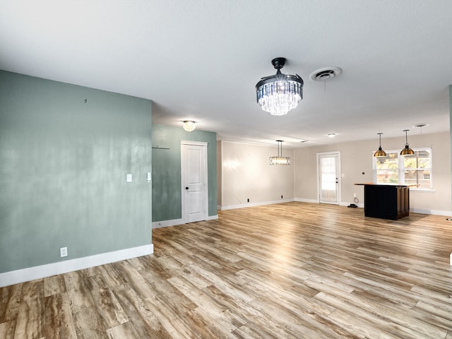 unfurnished living room featuring a chandelier and light wood-type flooring